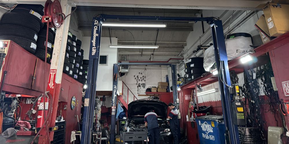 Inside GR Auto Center's bay: two Challenger lifts, a car with its hood up, and tires stacked on red cabinets.