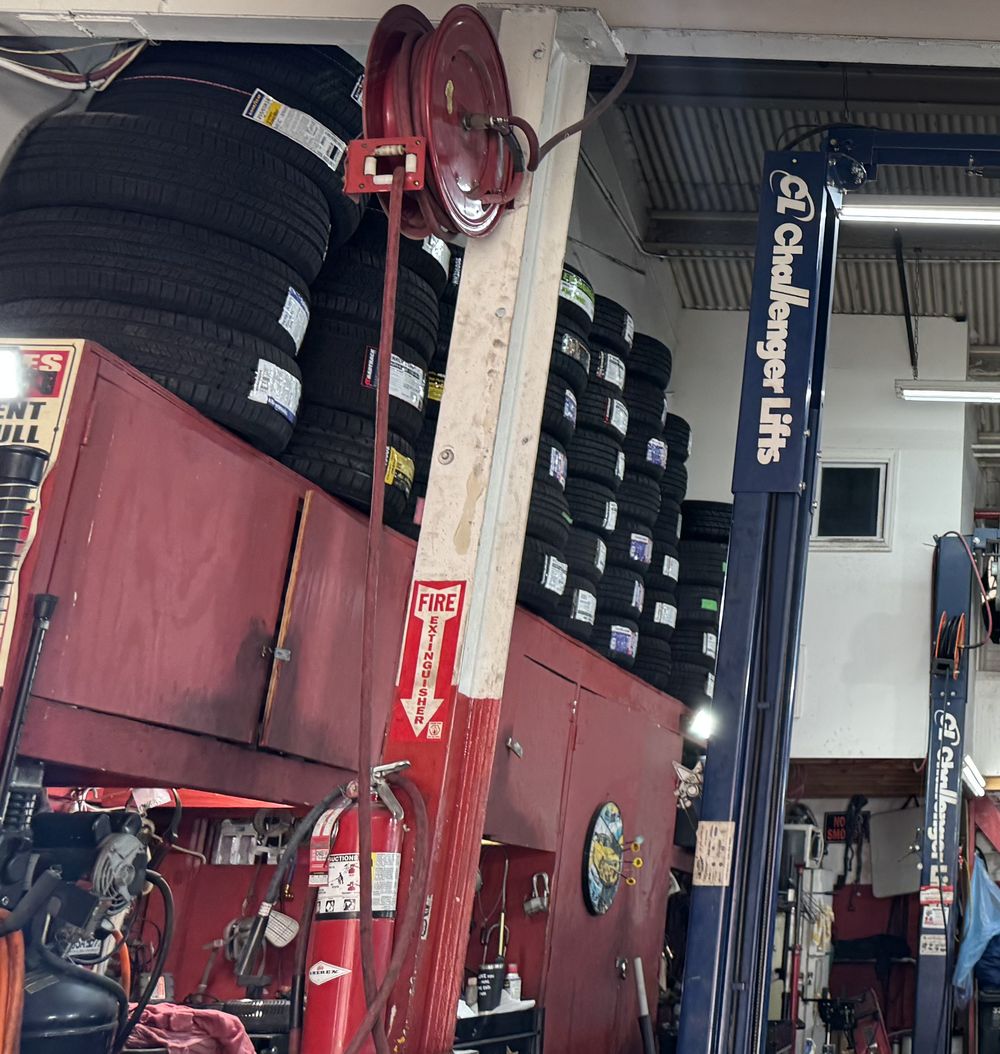 Racks of new tires stacked above red tool cabinets inside the shop.